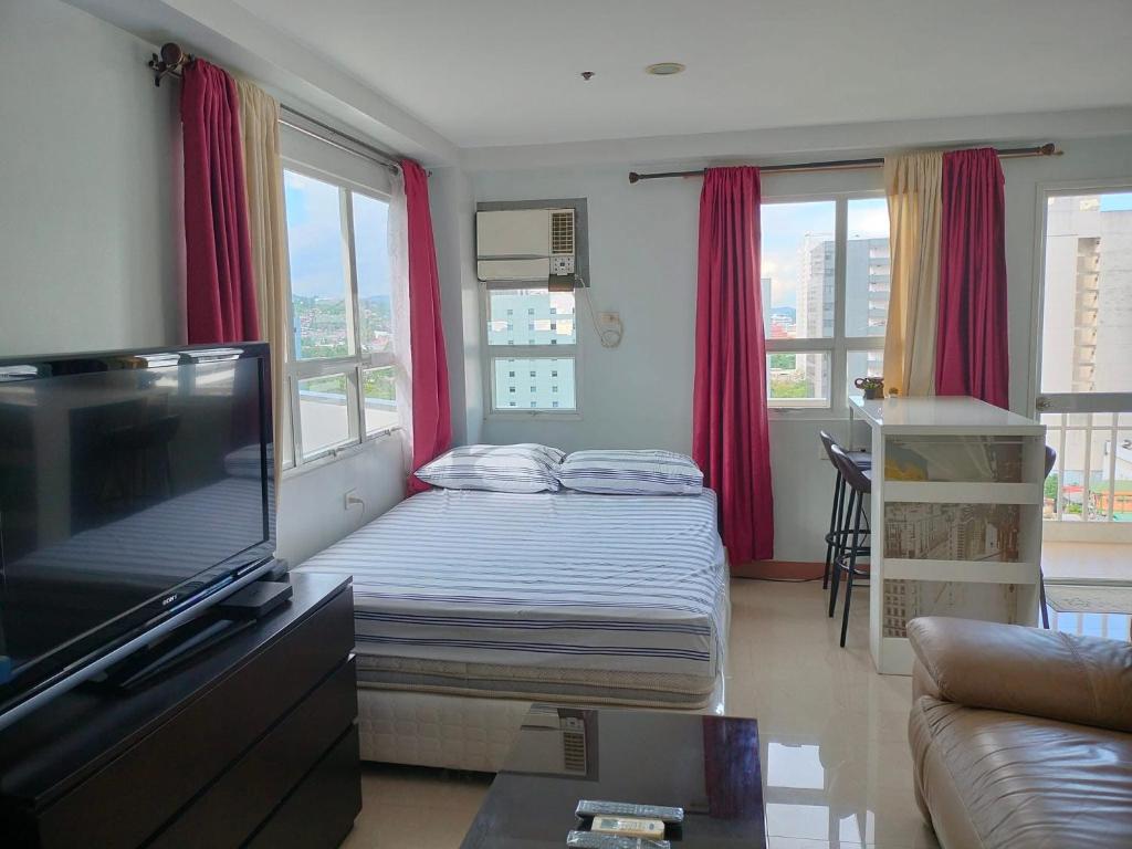 a living room with a bed and a flat screen tv at Penthouse A Near IT Park in Cebu City