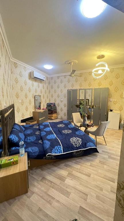 a bedroom with a blue bed and a desk and a table at غرف نوم في الخوض in Ḩayl Āl ‘Umayr