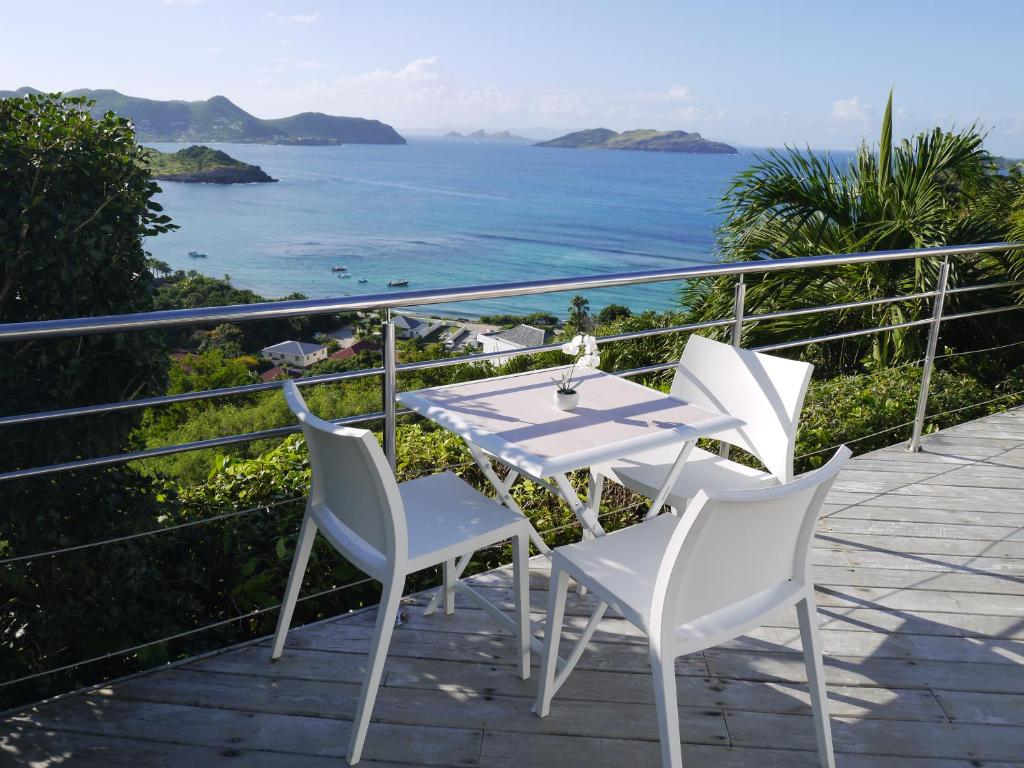 een witte tafel en stoelen op een balkon met uitzicht op de oceaan bij Maison des Brin - Lorient Camaruche in Quartier de Lorient