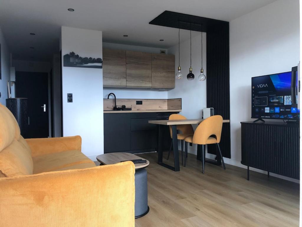 a kitchen and living room with a couch and a table at Studio vue sur la mer in Neufchâtel-Hardelot