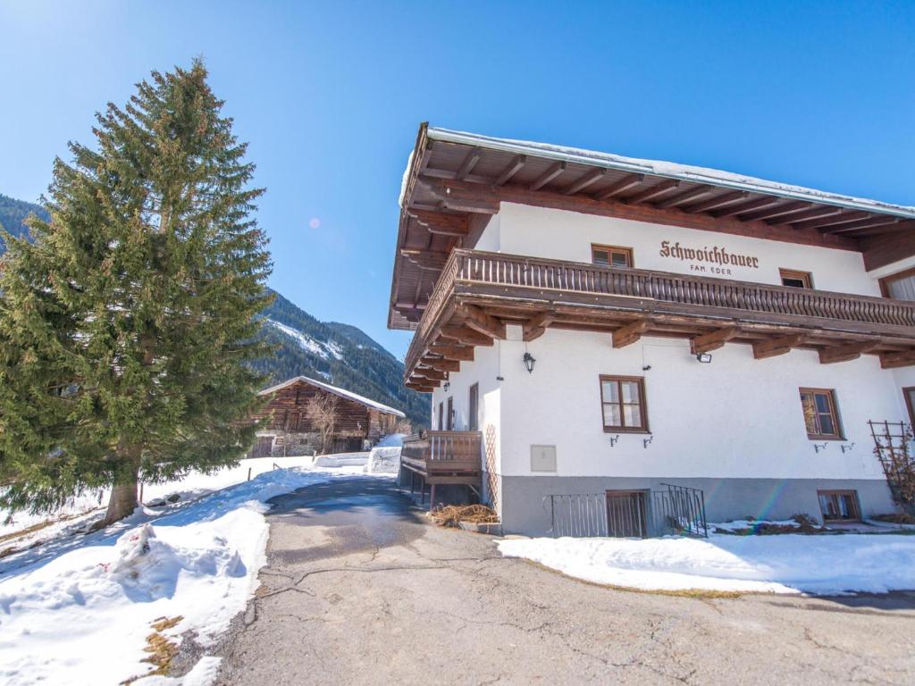 a large building in the snow with a tree at Schwoichbauer II in Saalbach Hinterglemm