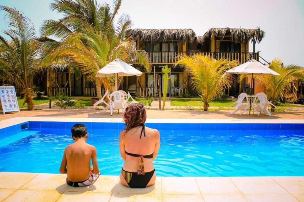 Ein Mann und eine Frau sitzen neben einem Pool in der Unterkunft La casa de Jessi in Máncora