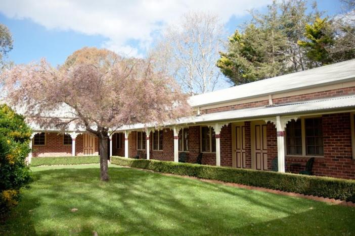 a tree in a yard next to a brick building at The Carrington Inn - Bungendore in Bungendore