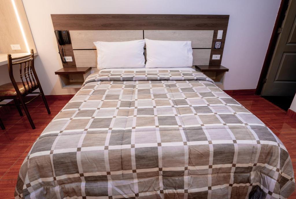 uma cama grande em um quarto com piso de madeira em Hotel INTI TUMI em Lima
