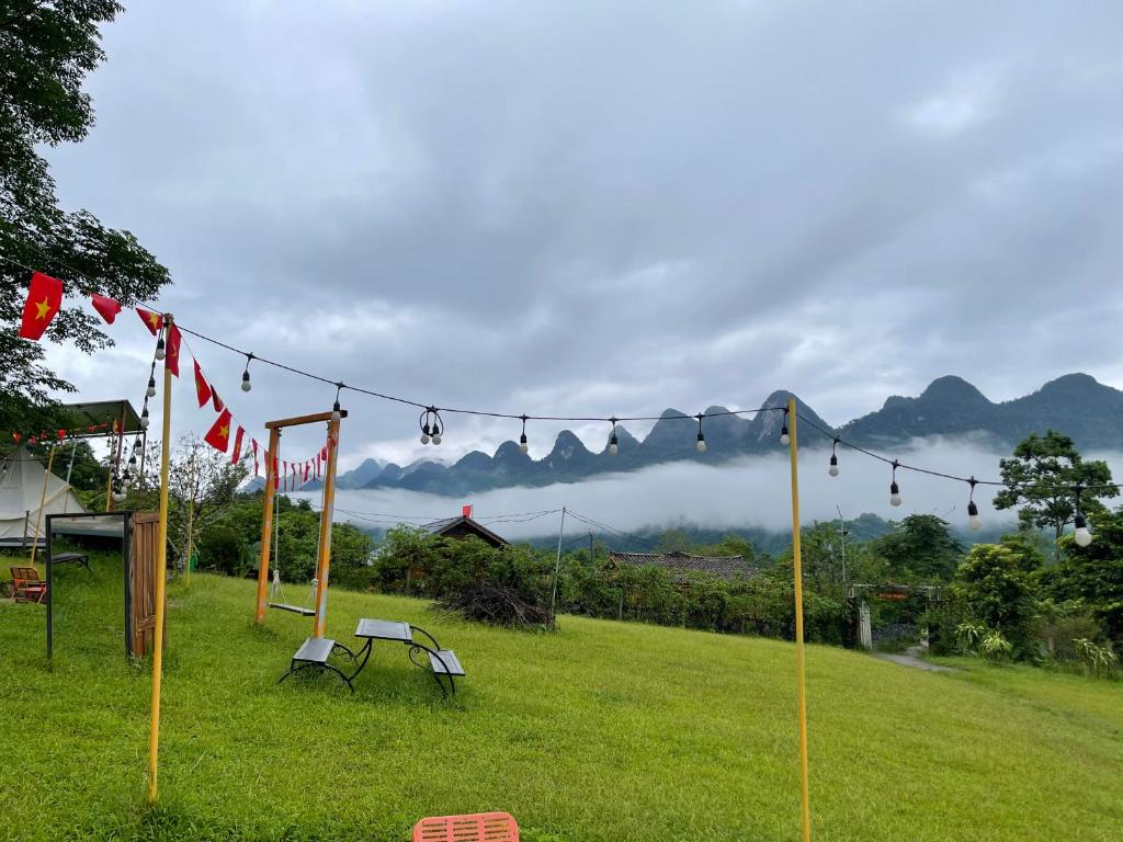a string of flags on a field with mountains in the background at Đồi Gió Homestay & Campsite in Ha Giang