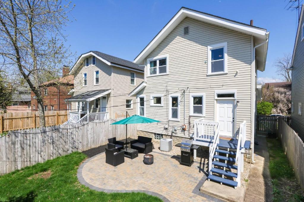 ein Haus mit einer Terrasse mit zwei Stühlen und einem Sonnenschirm in der Unterkunft Modern 3BR w Yard Garage in Columbus
