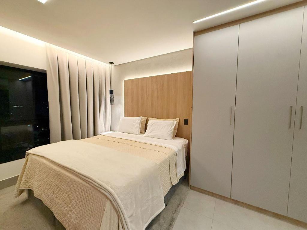 a bedroom with a white bed and a cabinet at Studio Soberano - O mais luxuoso de CG in Campo Grande