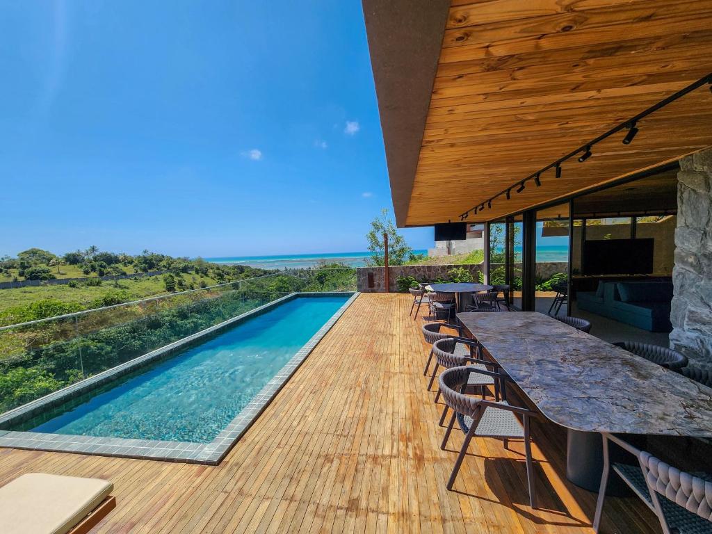 einen Pool mit einem Tisch und Stühlen auf einer Terrasse in der Unterkunft Casa do Alto - Milagres in São Miguel dos Milagres