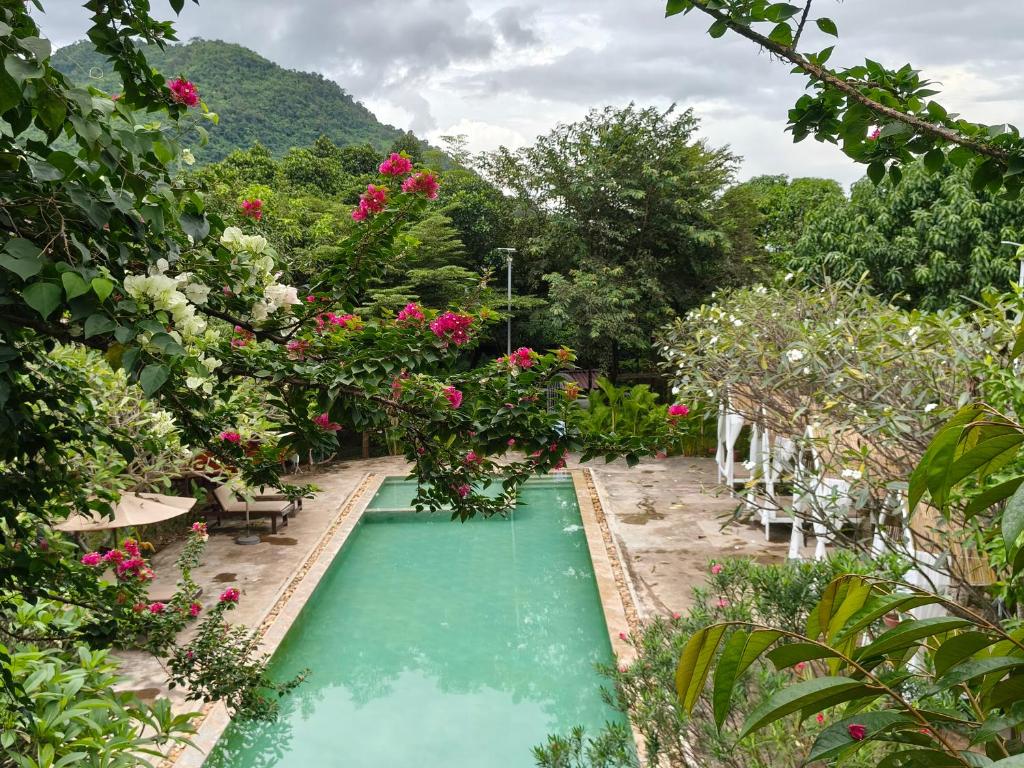 a swimming pool in a garden with pink roses at Boreirom TeukChhou lodge By JK6 in Phum Mak Prang