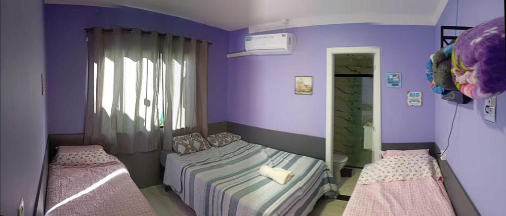 a bedroom with two beds and a mirror at Hotel Pousada Sol Nascente Mafraa in Mafra