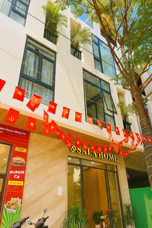 a building with red flags in front of it at Sala Home Móng Cái in Móng Cái