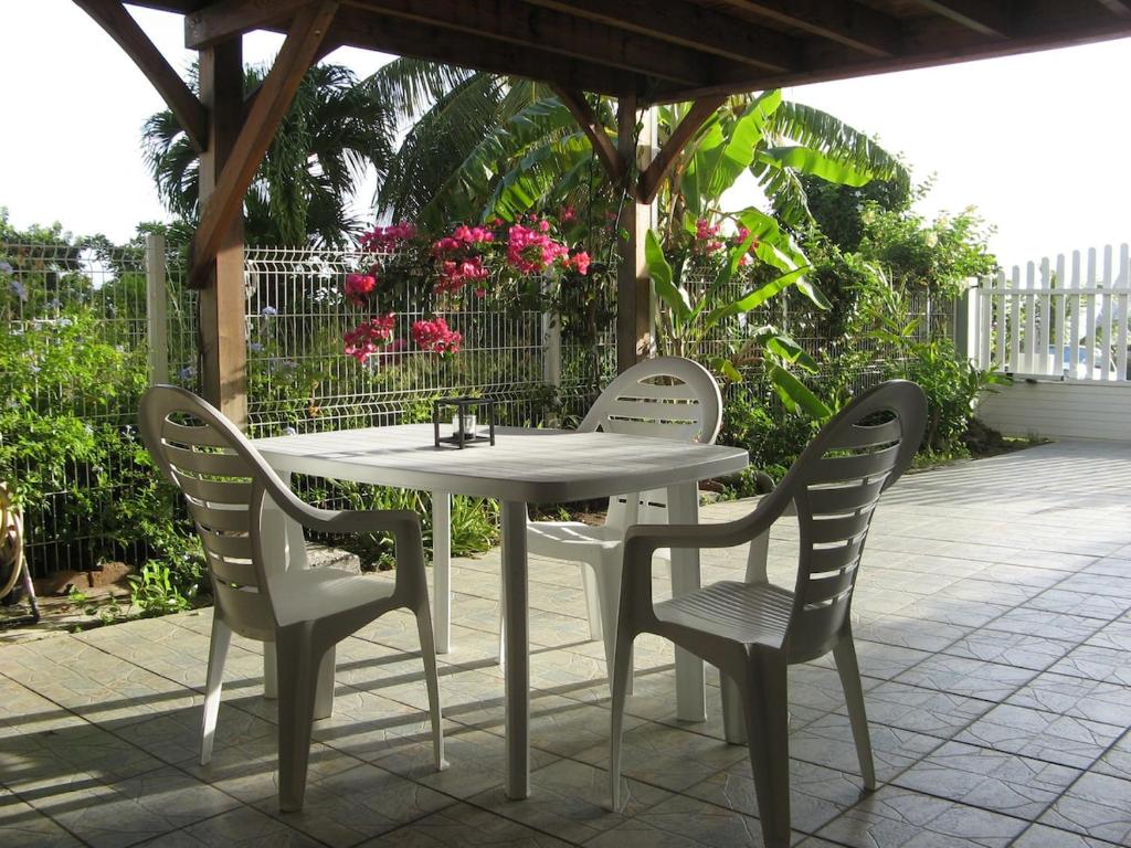 a white table and four chairs on a patio at LOGEMENT REZ DE JARDIN A 4mn DES PLAGES in Case-Pilote