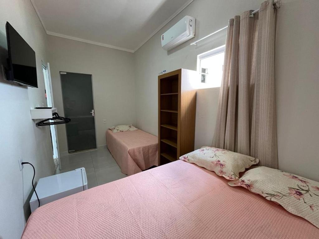 a small bedroom with two beds and a tv at Pousada Luz do Sol in Piranhas