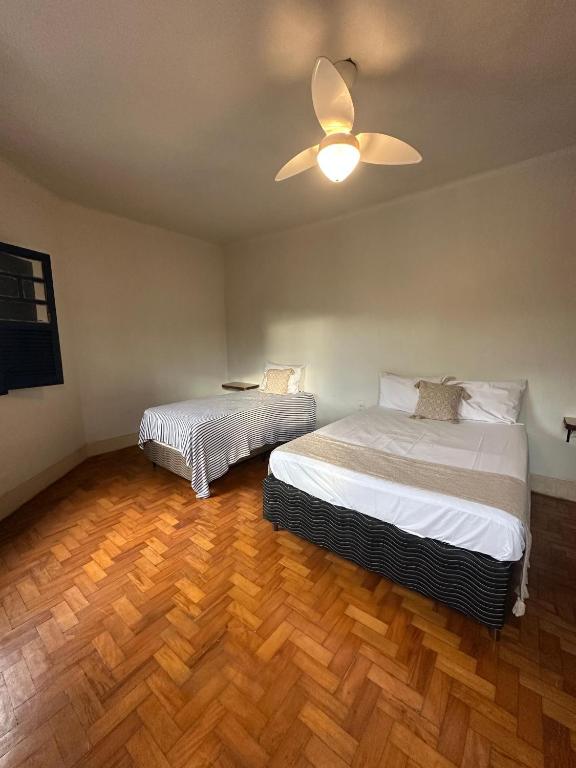 a bedroom with two beds and a ceiling fan at Oxx Quarto Terra in Congonhas