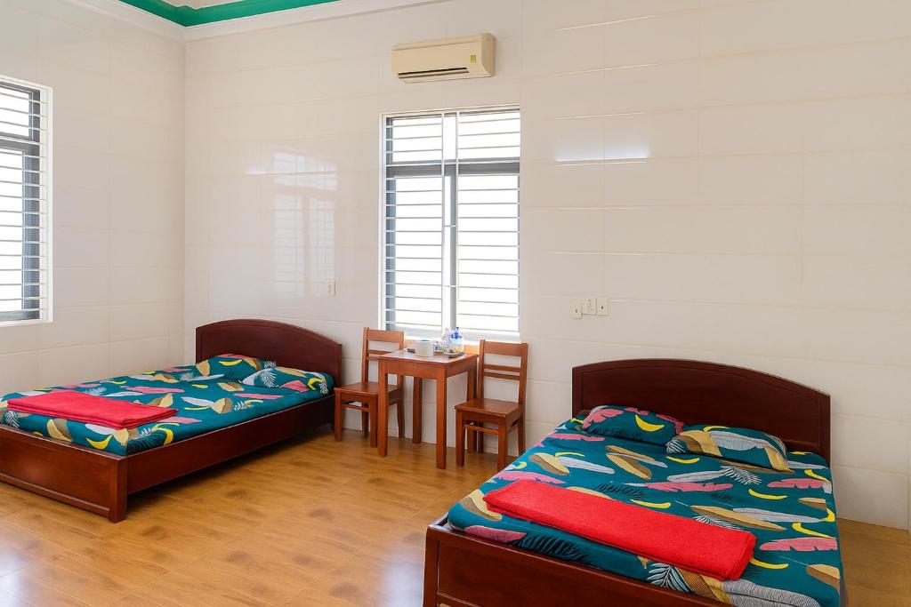 een kamer met 2 bedden en een tafel met een tafel bij Cường Thu Motel Quảng Trị in Xã Thanh Trạch