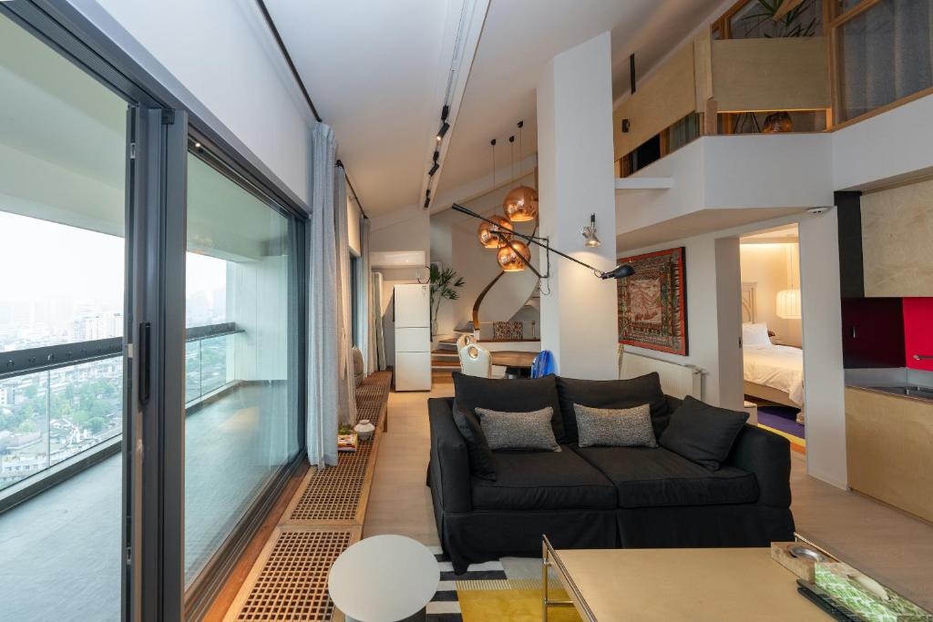 成都市にあるChengdu Kuanzhai Yuntu Serviced Apartmentのリビングルーム(黒いソファ、大きな窓付)