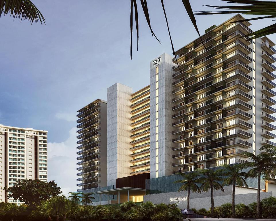 a tall building with palm trees in front of it at Grand Hyatt Cancun Beach Resort in Cancún
