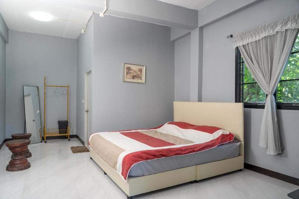 a bedroom with a bed with a red and white blanket at วิวดี ป่าเหมี้ยง โฮมสเตย์ in Ban Pa Miang