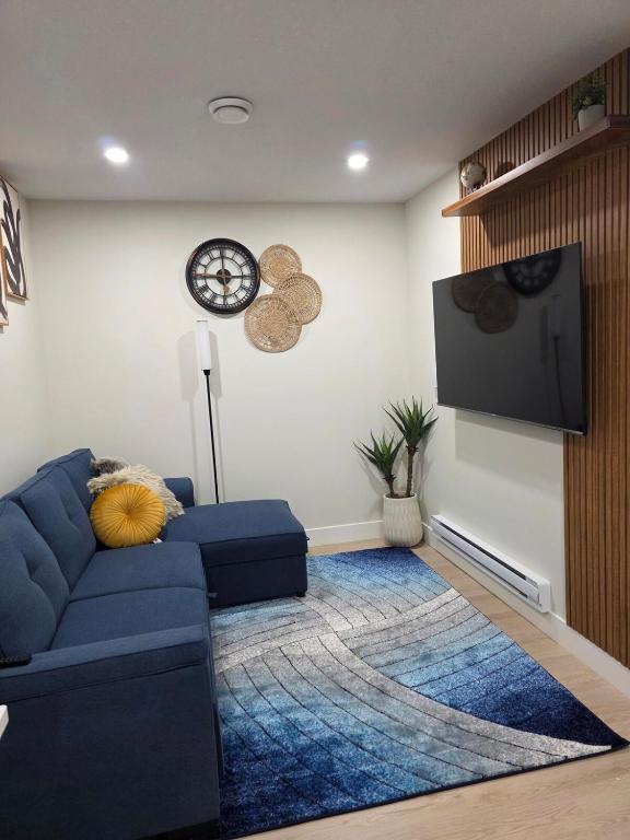 a living room with a blue couch and a tv at Cozy & Stylish 1BR Suite in Regina