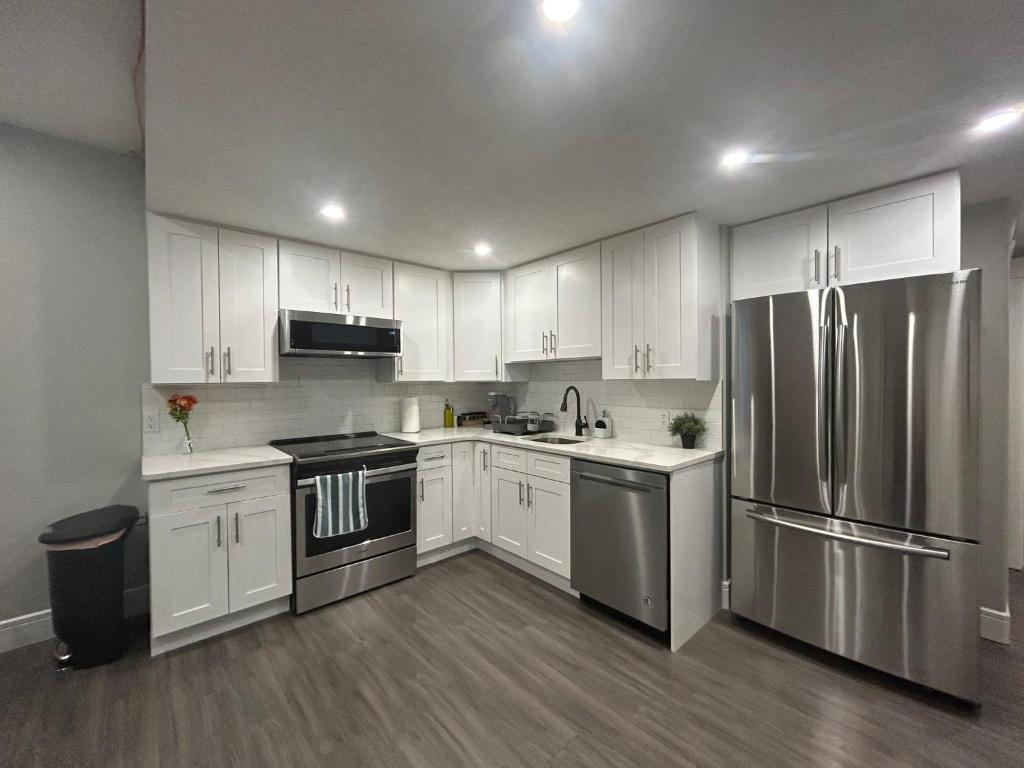 a kitchen with white cabinets and stainless steel appliances at Cozy Family Friendly Suite Near Whyte, UofA, Kinsmen with Desks or Home-office and Full Kitchen in Edmonton
