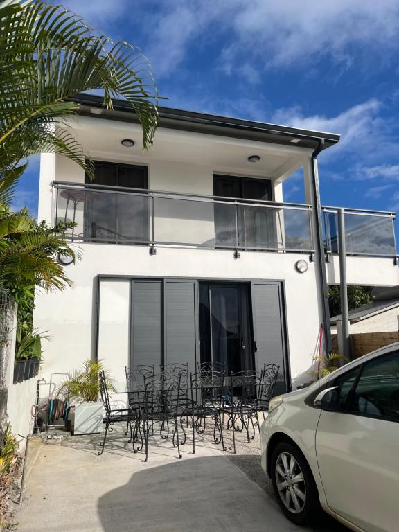 ein weißes Haus mit schwarzen Stühlen und einem Balkon in der Unterkunft Maison neuve, agréable avec vue mer et montagne in Saint-Pierre