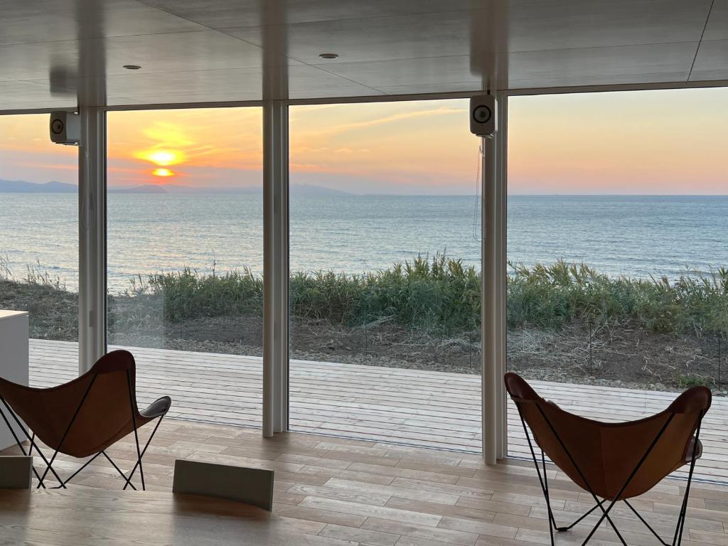 2 stoelen in een kamer met uitzicht op de oceaan bij Cliff House MORAI 2 