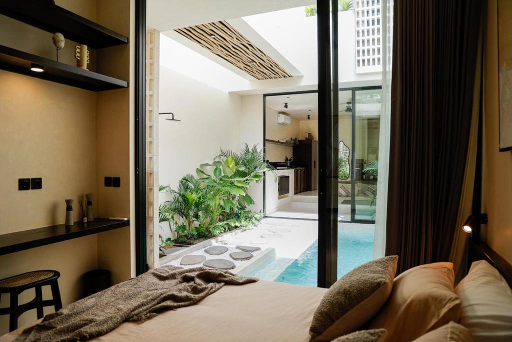 a bedroom with a bed and a view of a pool at Yugen Villas in Uluwatu