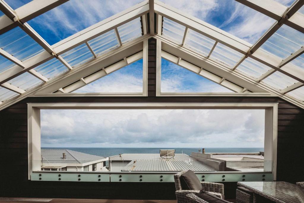 a large window in a room with a view of the ocean at Buller Noire - luxury New Plymouth oceanview home in New Plymouth