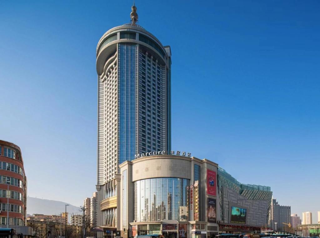 a tall building with a statue on top of it at Mercure Lanzhou Dongfanghong Square Hotel in Lanzhou