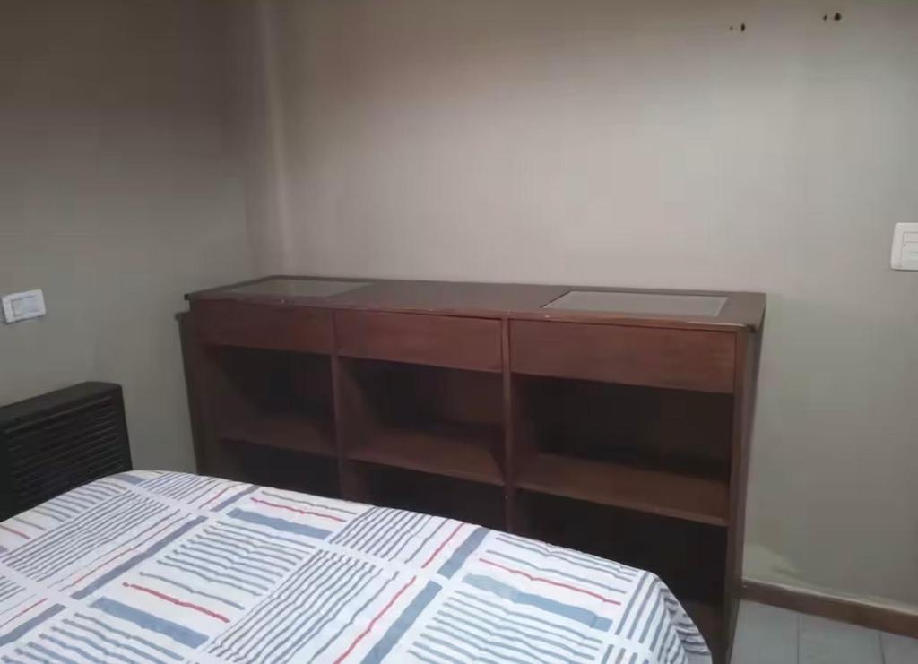 eine Holzkommode in einem Schlafzimmer mit einem Bett in der Unterkunft Casa alquiler in Ostende