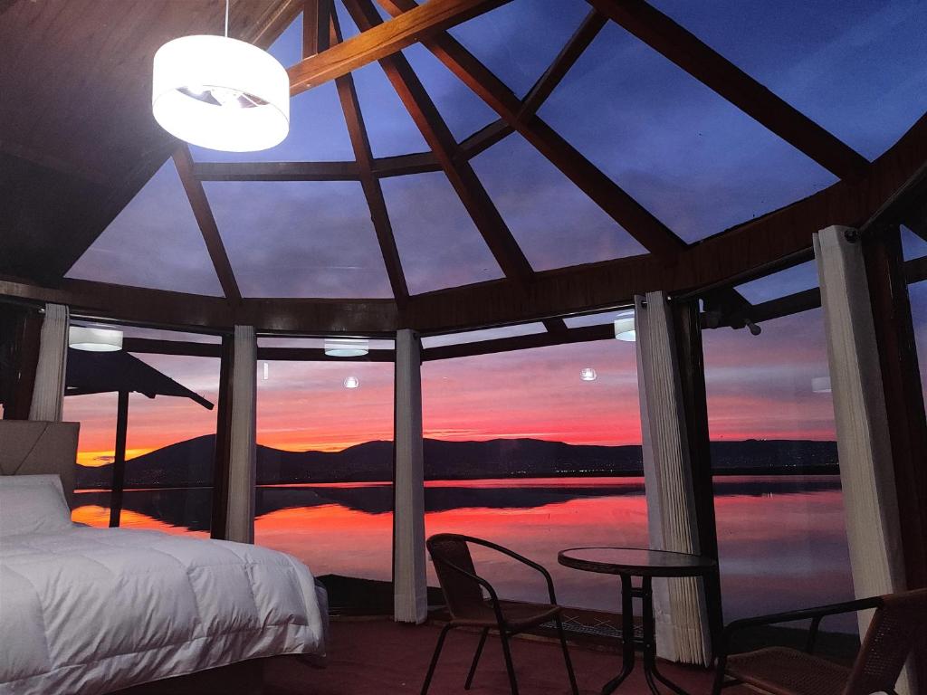 a room with a bed and a view of a sunset at Los uros Domo Atardecer in Puno