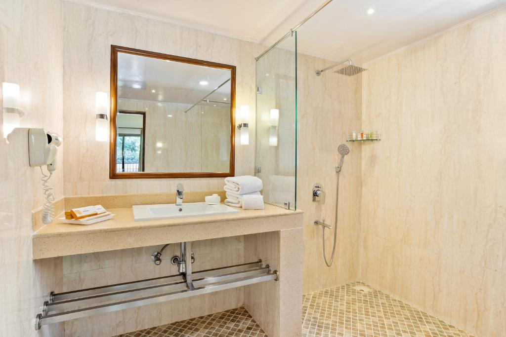 um banheiro com pia e chuveiro em Seashell Suites and Villas- Candolim Goa em Candolim