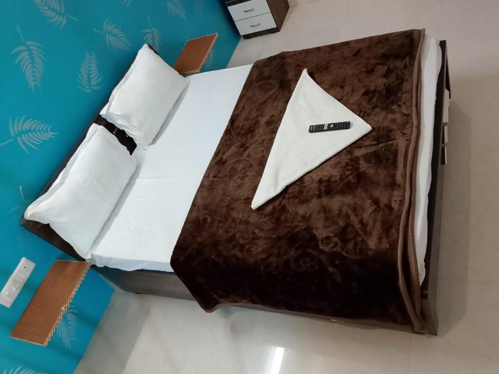 a bed with a white pillow and a napkin on it at hotel shreejee in Himatnagar