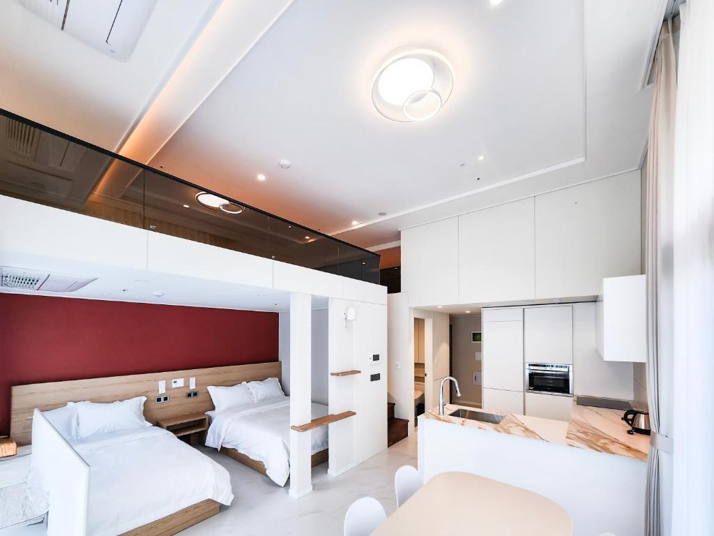 a bedroom with two beds and a kitchen at Paramion Hotel in Busan