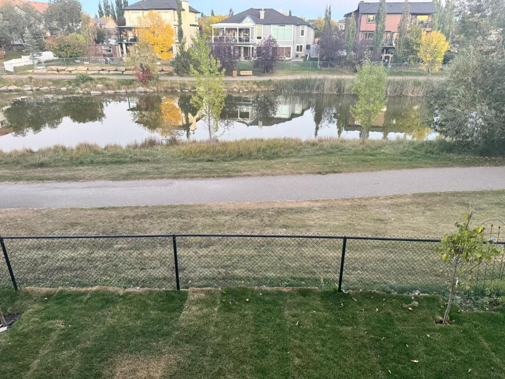 una cerca frente a un cuerpo de agua en Walkout basement suite with canal view near airport, en Airdrie