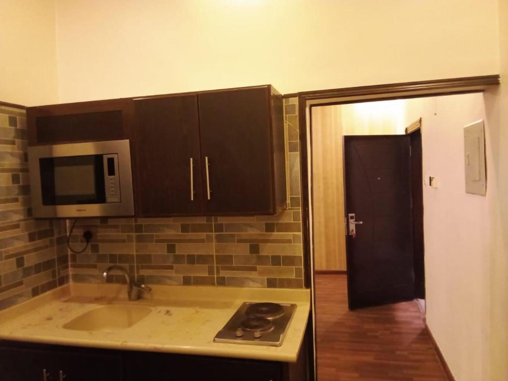 a kitchen with a sink and a microwave at اصيل الفاخره المخدومه in Taif