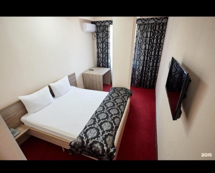 a small room with a bed and a tv at КзО in Shymkent