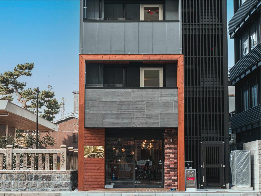 a red brick building with a window on a street at LiVEMAX Hostels Kyoto Ekimae in Kyoto