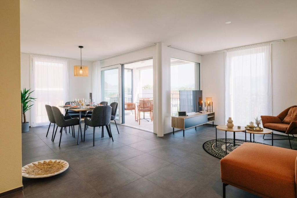 ein Wohnzimmer mit Tisch und ein Esszimmer in der Unterkunft Apartment Stockhorn in See- und Bergnähe, modern, mit Balkon, 4 Gäste in Einigen