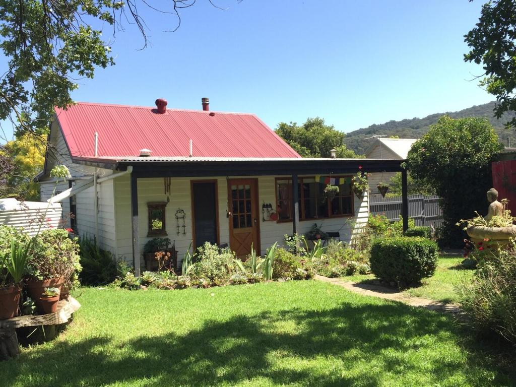 une petite maison blanche avec un toit rouge dans l'établissement PET Friendly Miners Cottage 'Baraka BnB', à Kalorama