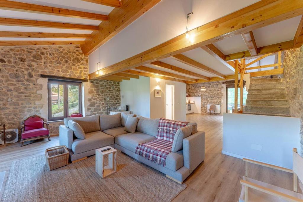 a living room with a couch and a stone wall at The Stone House naturaleza y confort in Santibáñez de Villacarriedo