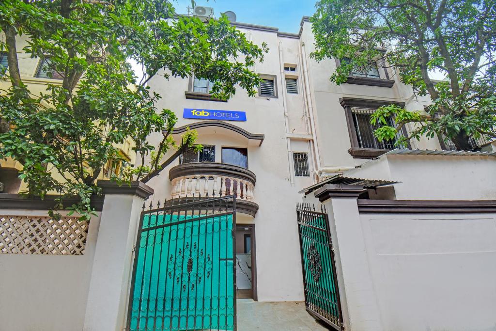 a white building with a green gate and a fence at Via The Heaven in Pune