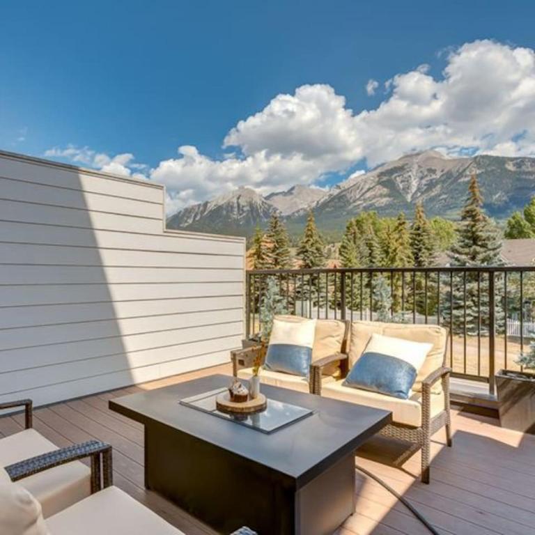 a balcony with a table and chairs and mountains at Stunning Modern 2BR Unit in Downtown Canmore in Canmore