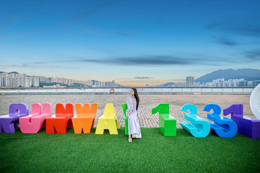 香港にあるRunway 1331 - Enlightの「遊び」と書かれた看板の前に立っている女性