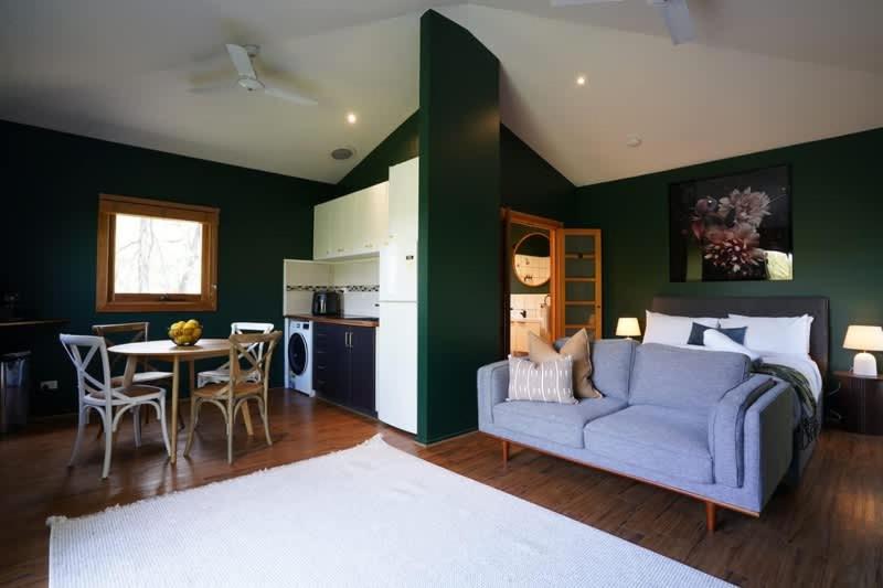 a living room with a blue couch and a table at Central studio with spabath in Daylesford