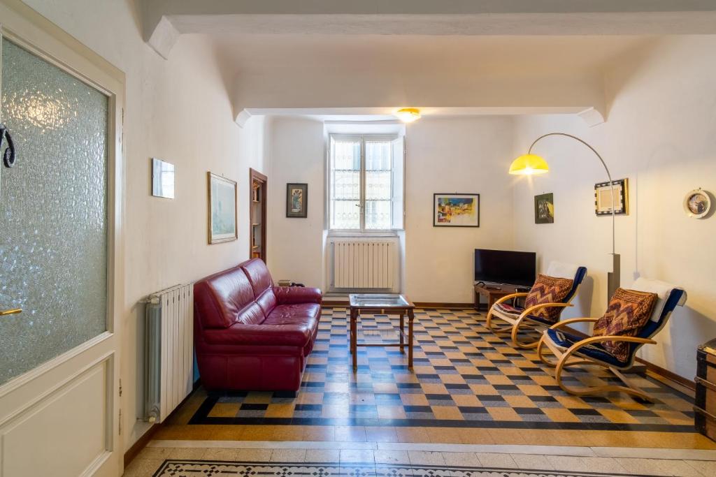 ein Wohnzimmer mit einem roten Sofa und Stühlen in der Unterkunft La chiave del tempo in Lucca