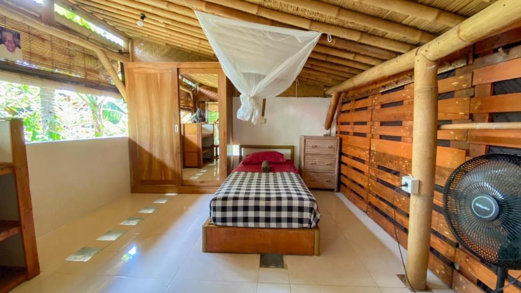 a bedroom with a bed in a room with wooden walls at Serenity Eco Guesthouse - CHSE certified in Canggu
