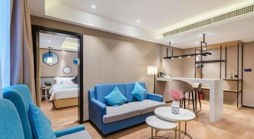 a living room with a blue couch and a bedroom at Xana Lite· Zhengzhou Provincial Center Store in Zhengzhou