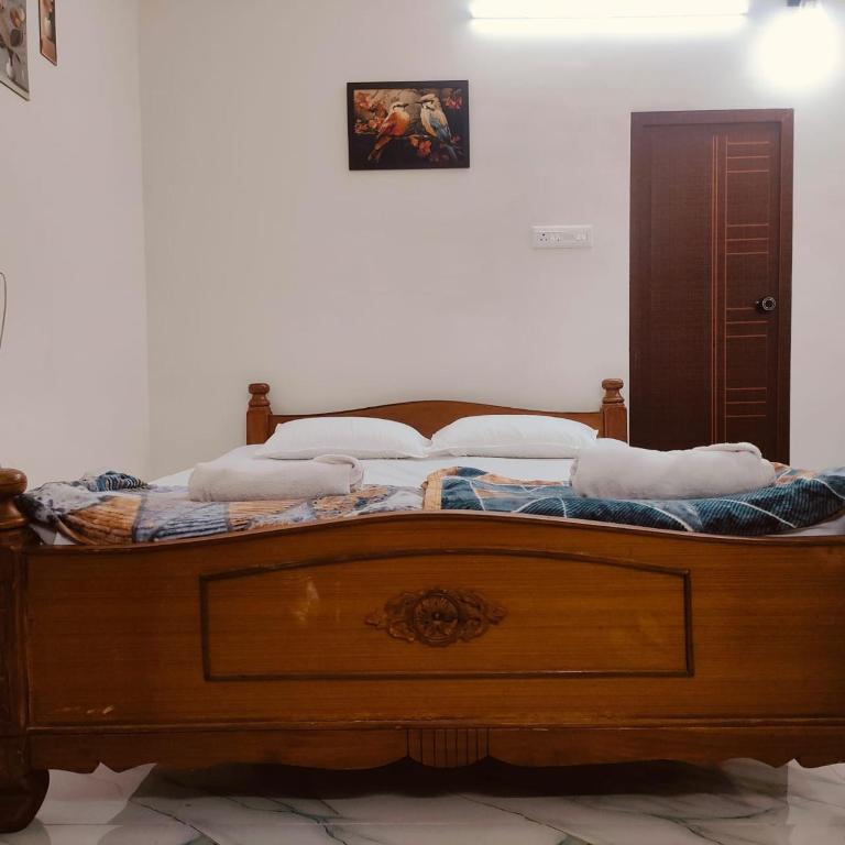 a bedroom with a wooden bed with pillows on it at Ebenezer Stay in Trivandrum