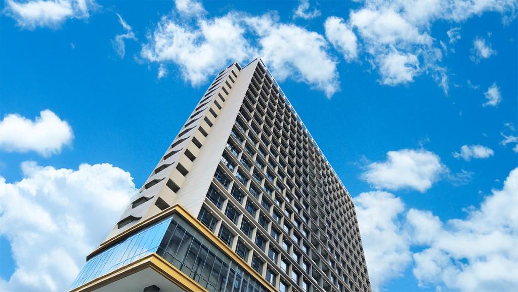 a tall building against a blue sky with clouds at HARRIS Hotel & Suites Nagoya Batam in Nagoya